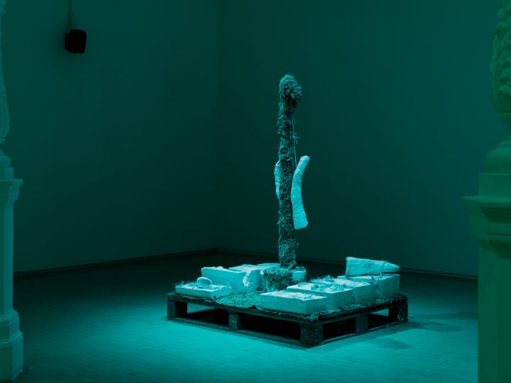 A mixed material sculpture by Ashley Holmes in the middle of a room, bathed in blue light.